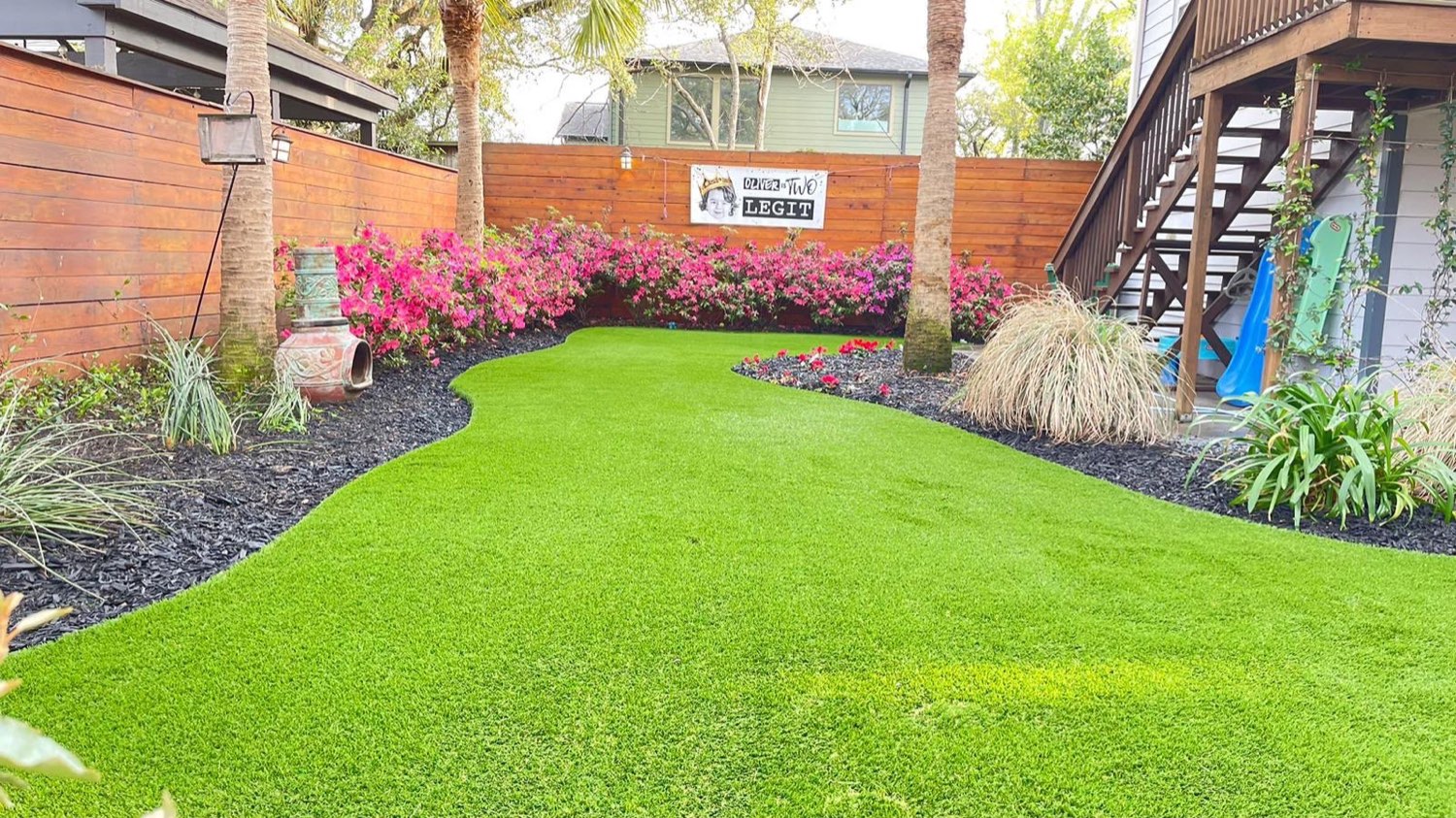 Jardín residencial con grama artificial y azaleas